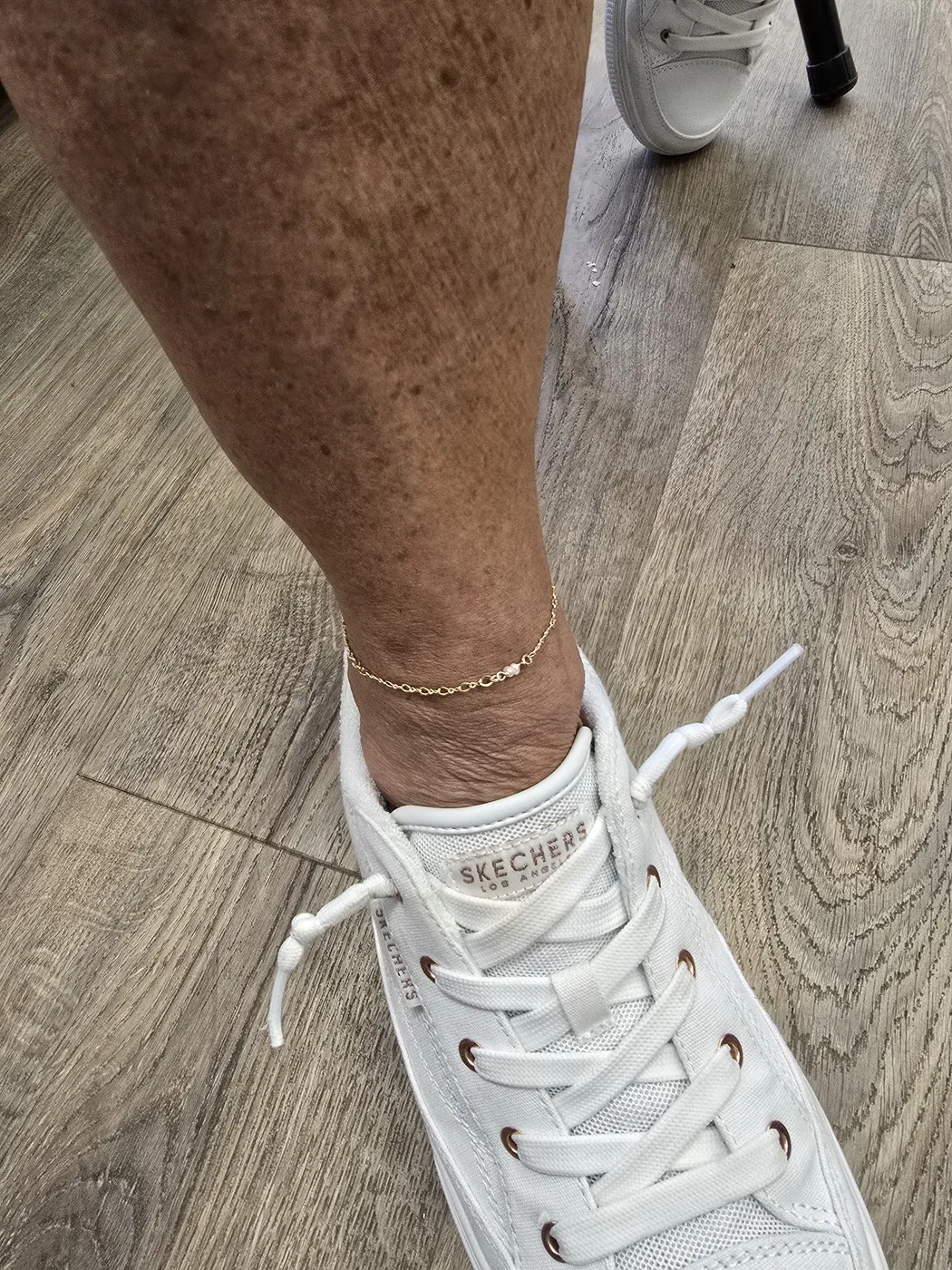 Thin gold anklet worn with white sneakers