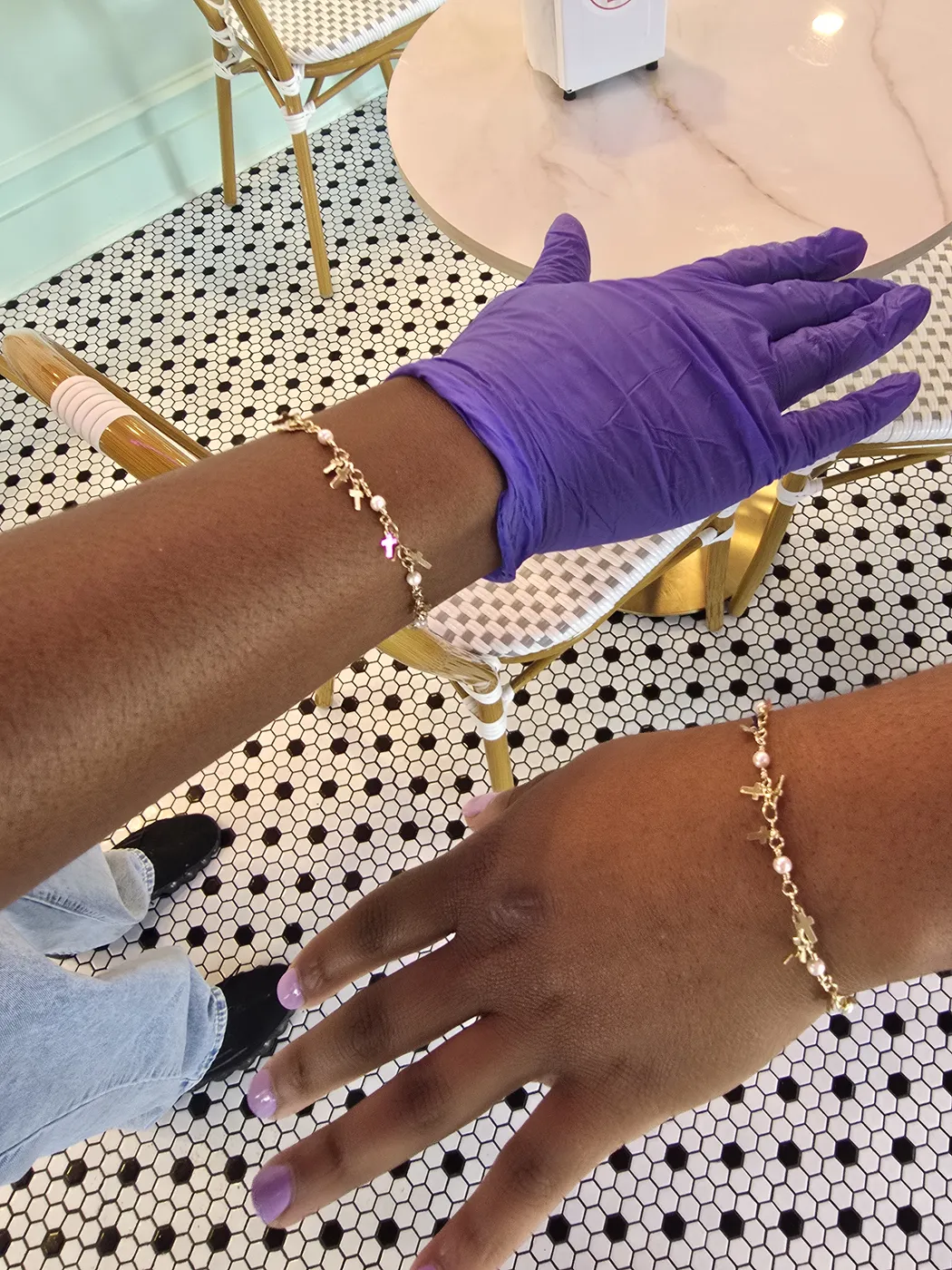 Gold bracelet with tiny charms being fitted on a client's wrist