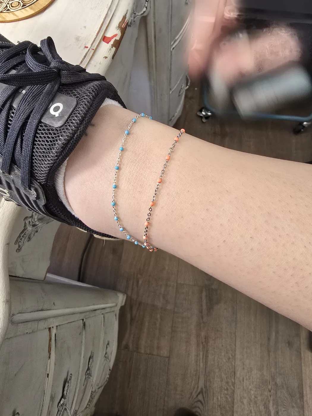 Two fine anklets, one beaded and one rose-toned, on a client's ankle