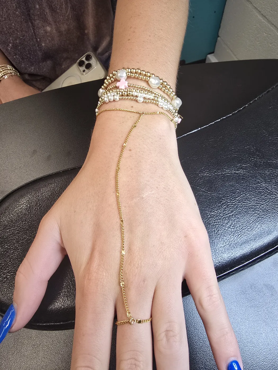 Hand chain linking a gold bracelet to a ring, with a bracelet stack
