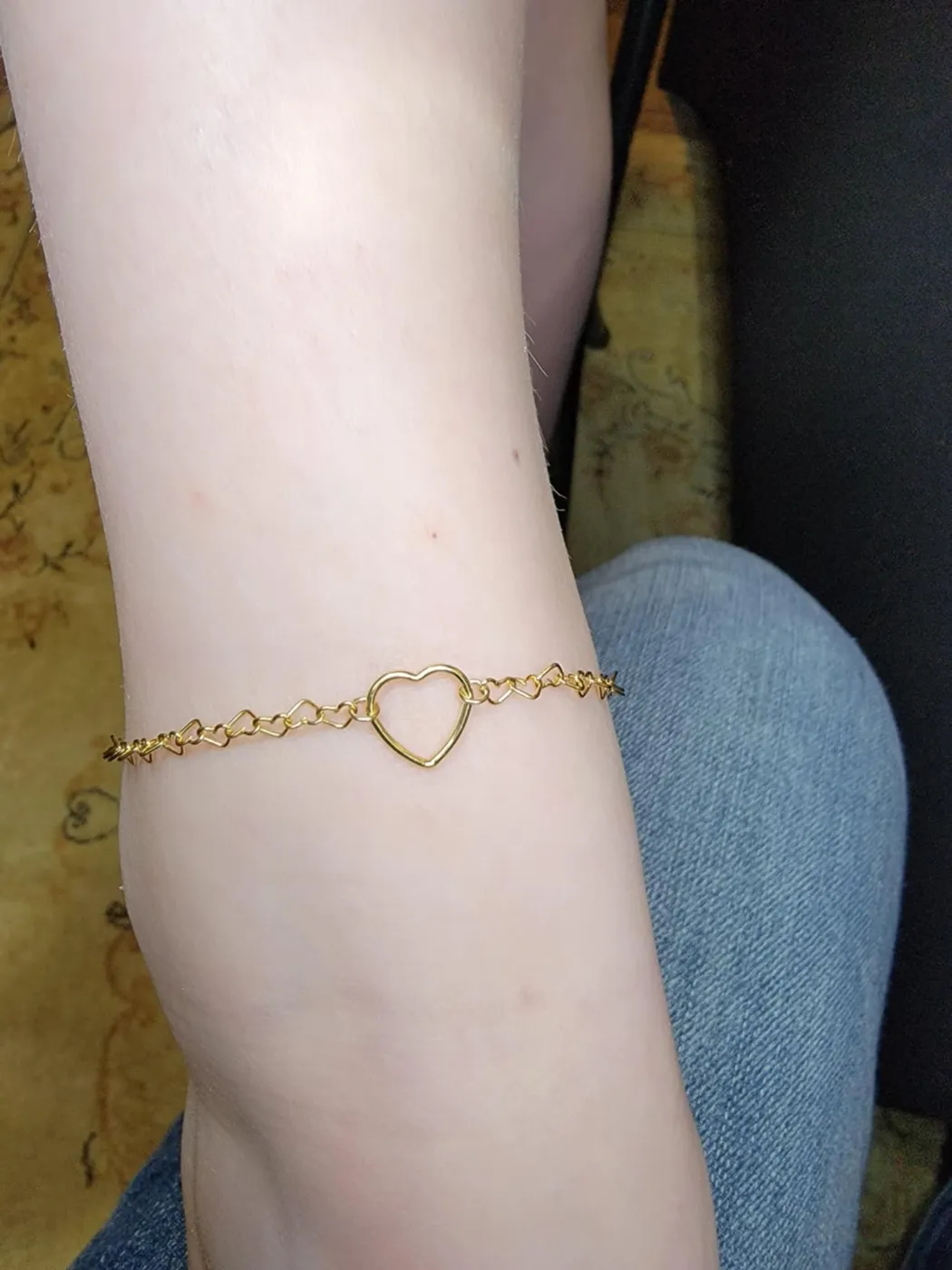 Gold chain with an open heart link worn on a client