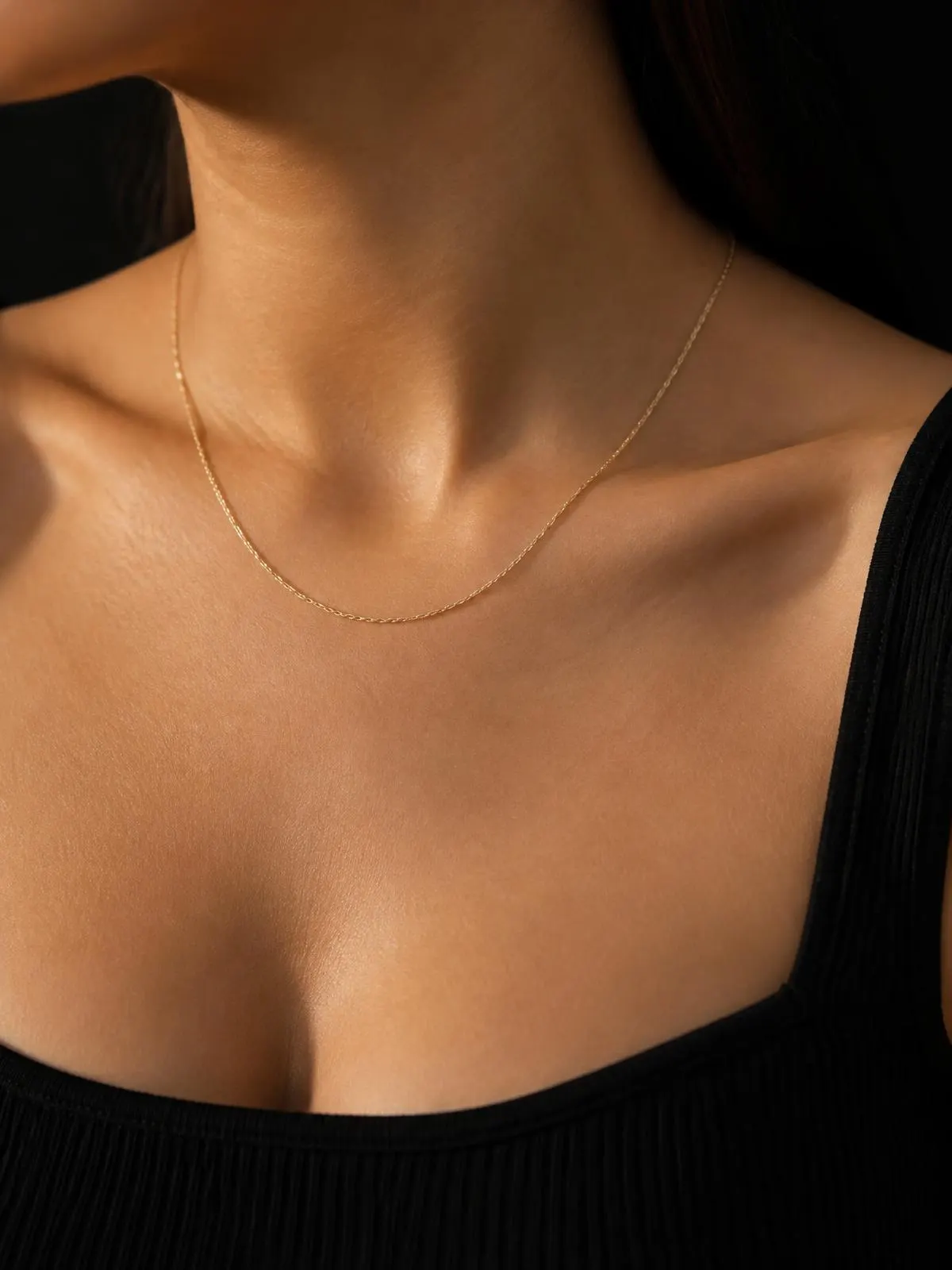Fine gold chain necklace resting on a collarbone in warm light