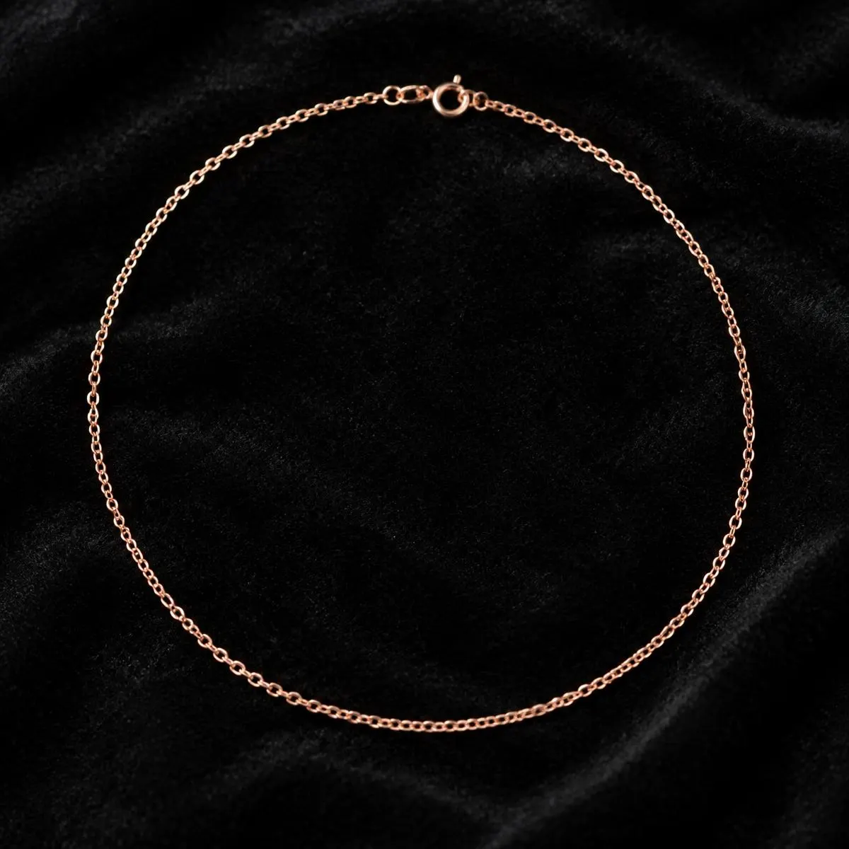 Rose gold chain forming a circle on black velvet