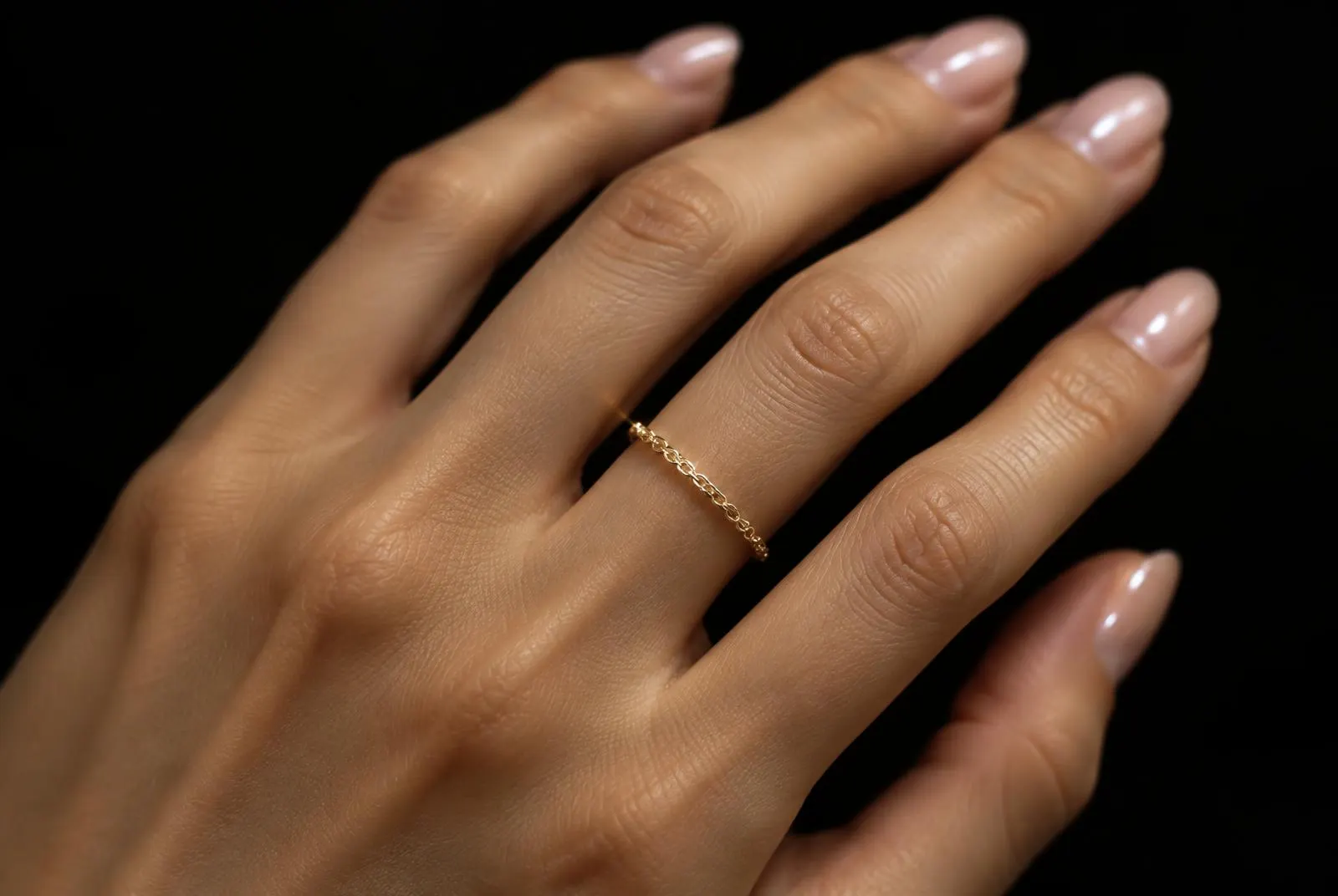 Delicate gold chain ring on a finger